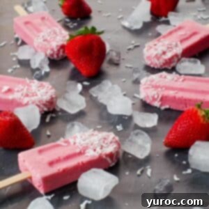 Close-up of creamy strawberry yogurt popsicles on a dark surface, surrounded by ice and fresh strawberries, highlighting their appealing texture.