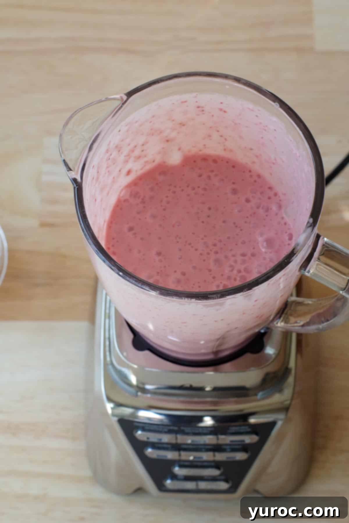 The strawberry yogurt popsicle mixture has been thoroughly blended in a blender until smooth and creamy.