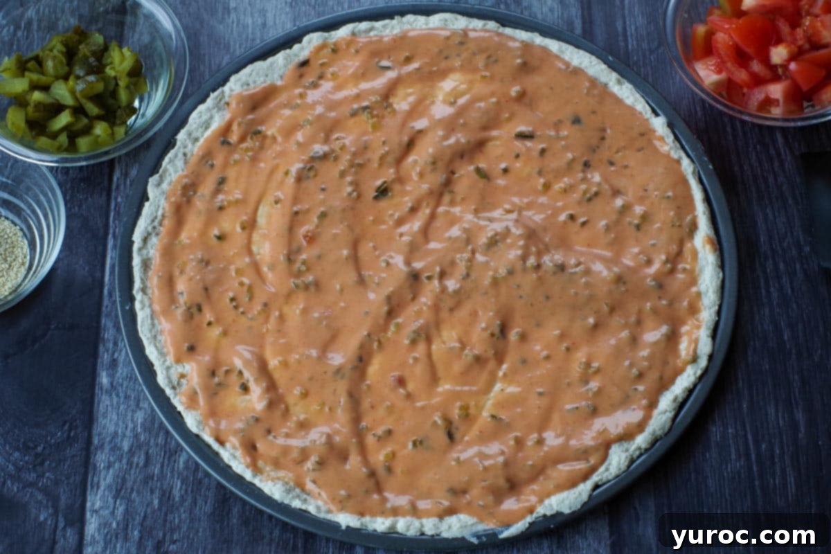 big mac pizza sauce spread on pizza dough