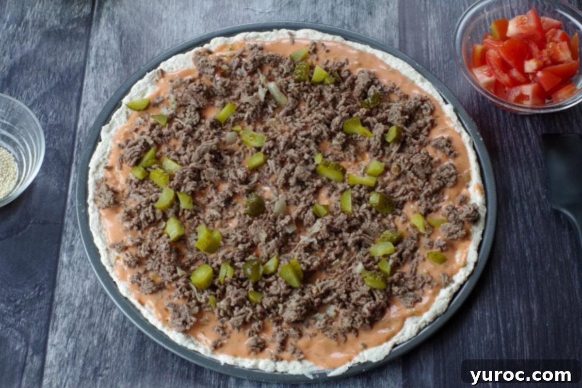 big mac pizza with sauce, cooked ground beef with onion and half the chopped pickles