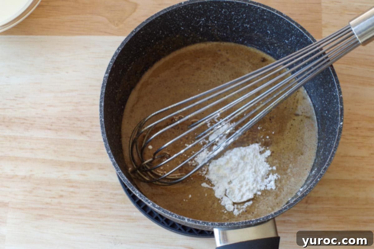 Effortless Butter Tart Dream Ice Cream 5 Butter tart mixture simmering in a saucepan with cornstarch added on top, ready to be whisked.