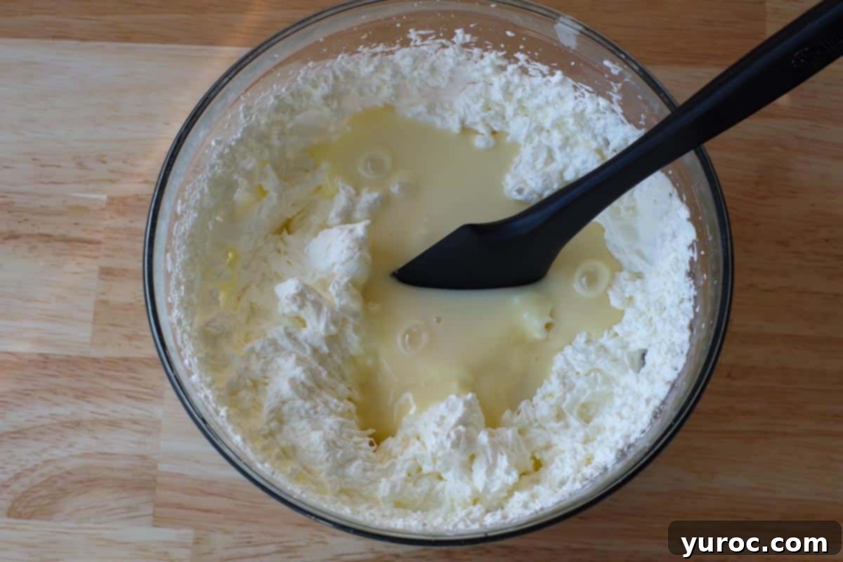 Effortless Butter Tart Dream Ice Cream 9 Sweetened condensed milk being poured into the bowl of stiffly whipped cream.