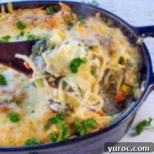 A close-up of creamy turkey tetrazzini on a spoon, hovering over a casserole dish, highlighting the rich texture and delicious appeal.