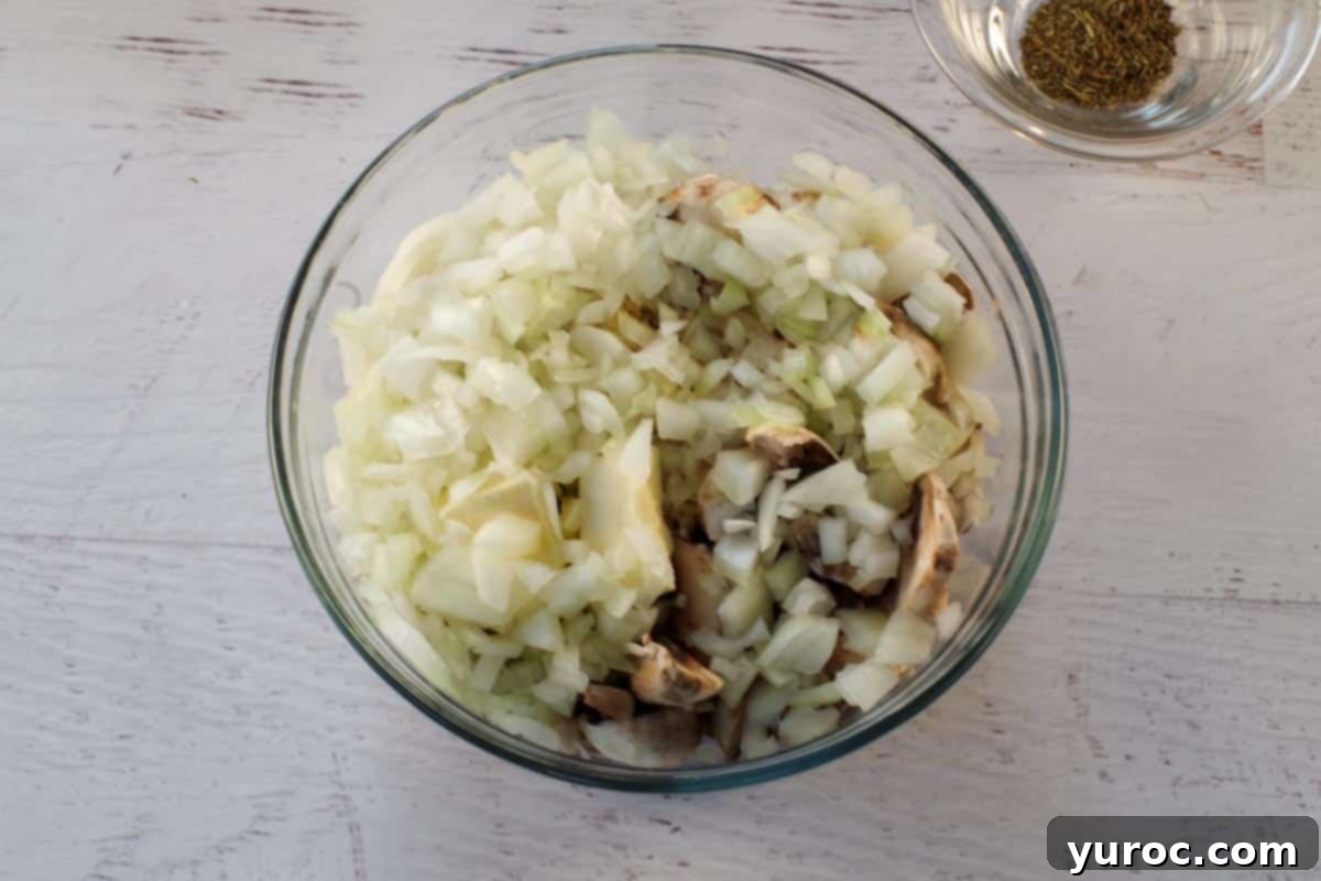 Chopped onions, fresh sliced mushrooms, butter, and salt combined in a medium glass bowl, ready for cooking.