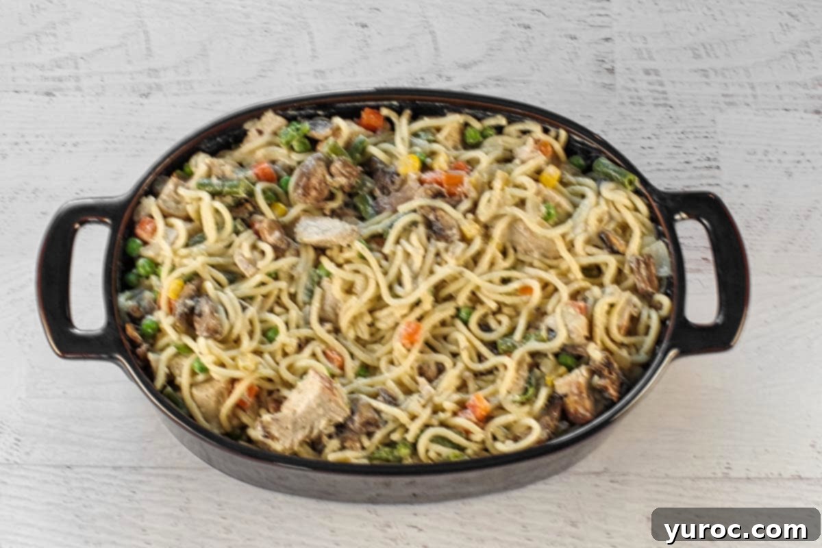 The creamy turkey tetrazzini mixture evenly distributed into a vibrant blue prepared casserole dish, ready for the final touches.