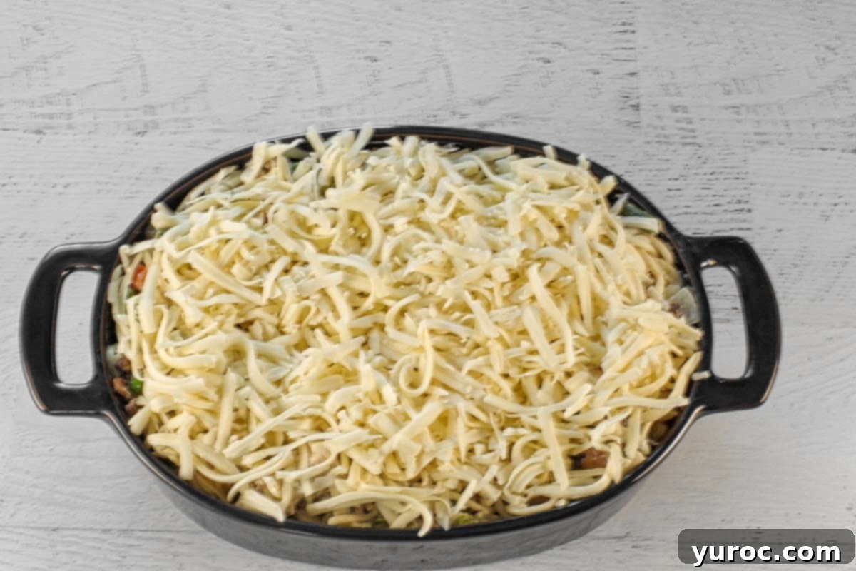 Generous amount of shredded mozzarella cheese sprinkled over the turkey tetrazzini mixture in the casserole dish, ready for baking.