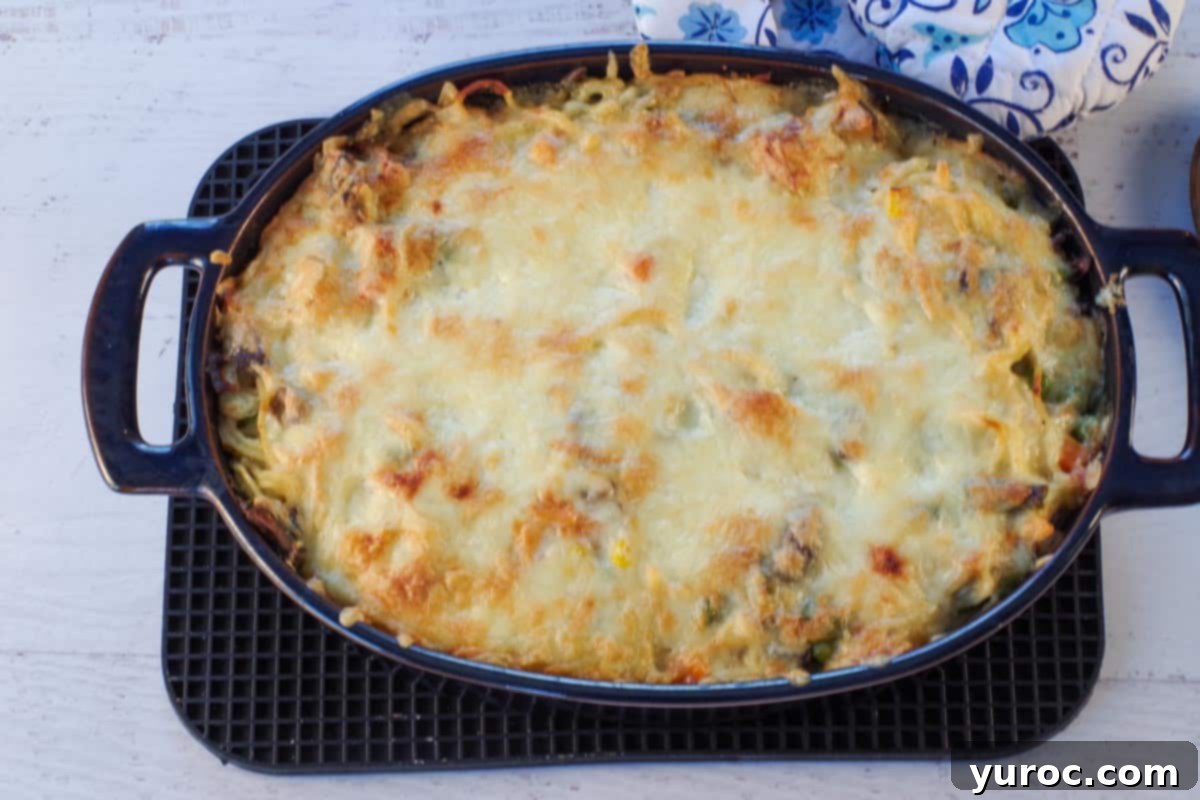 The baked turkey tetrazzini casserole, golden and bubbly with melted cheese, resting on a black trivet, fresh from the oven.