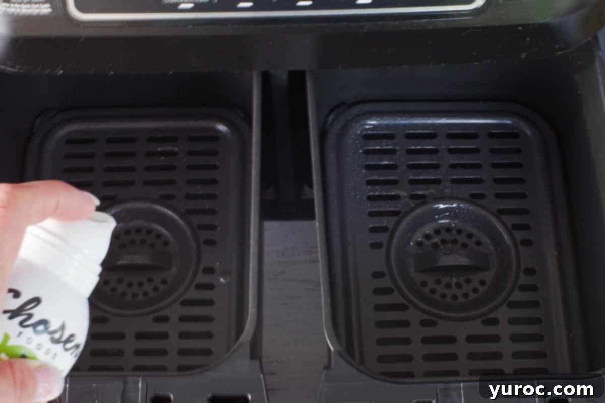 Crispy Air Fryer Falafel from Mix 5 inside of air fryer drawers being sprayed with cooking oil