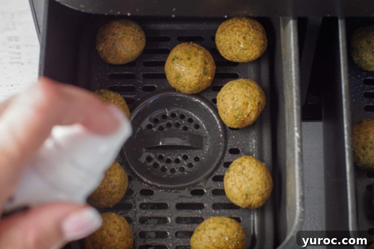 Crispy Air Fryer Falafel from Mix 8 Falafel balls being sprayed with 2-3 pumps of oil