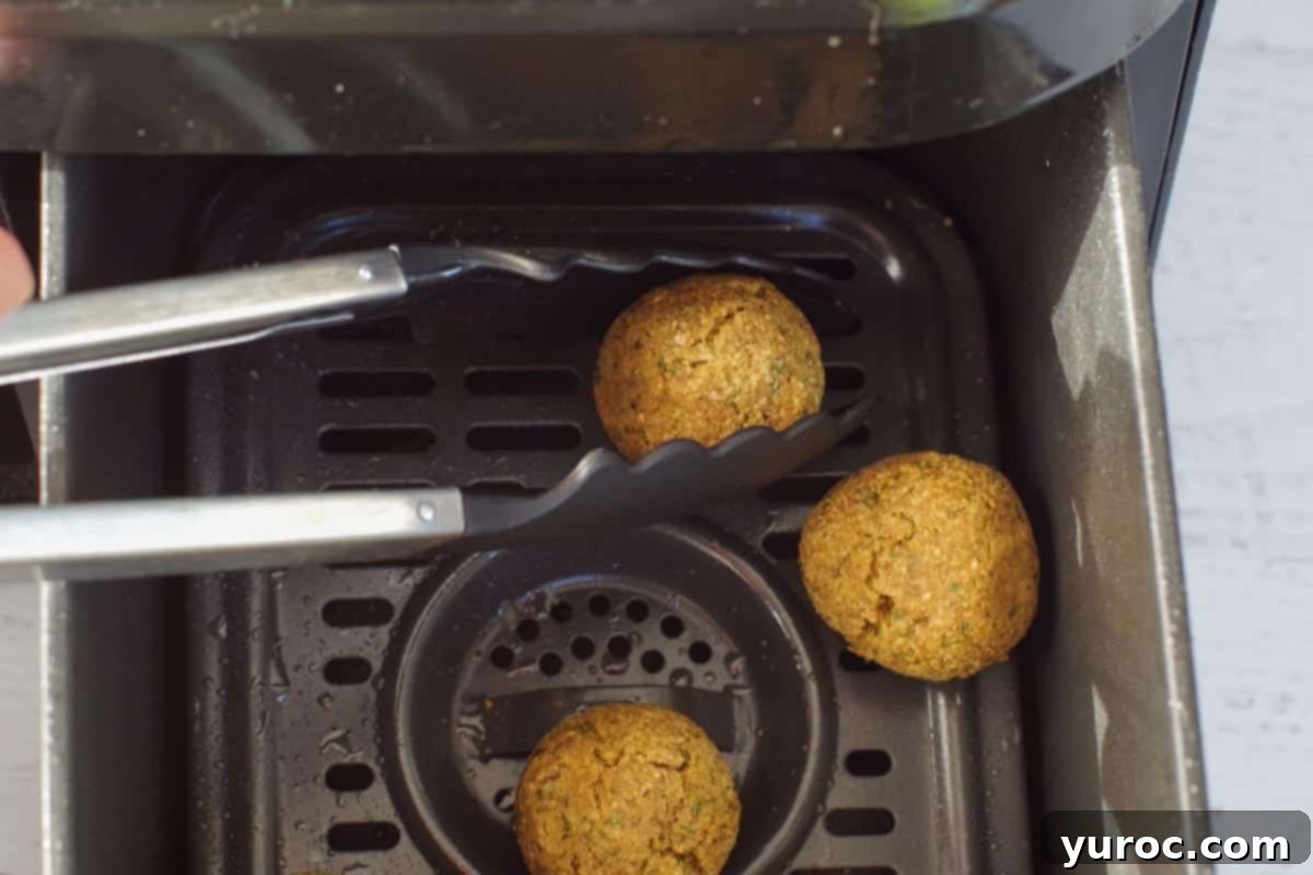 Crispy Air Fryer Falafel from Mix 9 cooked air fryer falafel being removed with silicone tongs