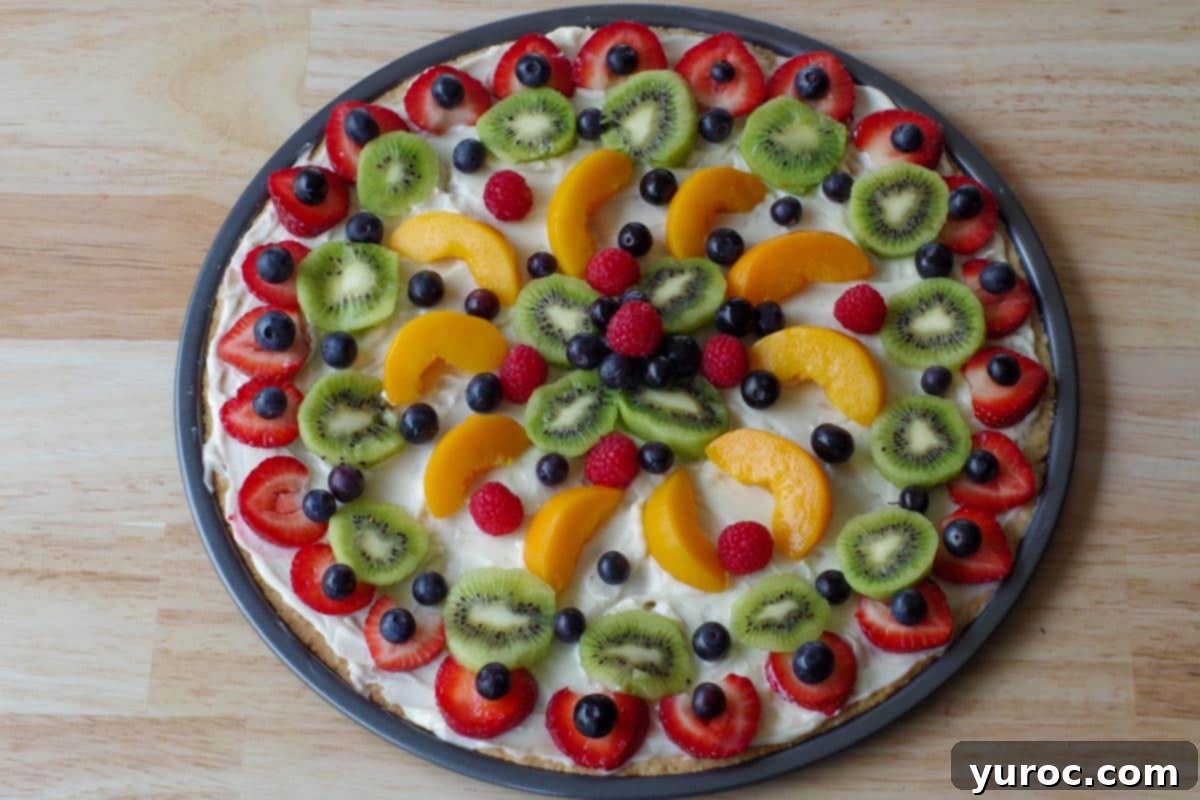 Vibrant Fruit Pizza with Sweet Glaze 12 A fully decorated fruit pizza, showcasing a vibrant and appealing arrangement of assorted fresh fruits like strawberries, blueberries, peaches, and kiwi.
