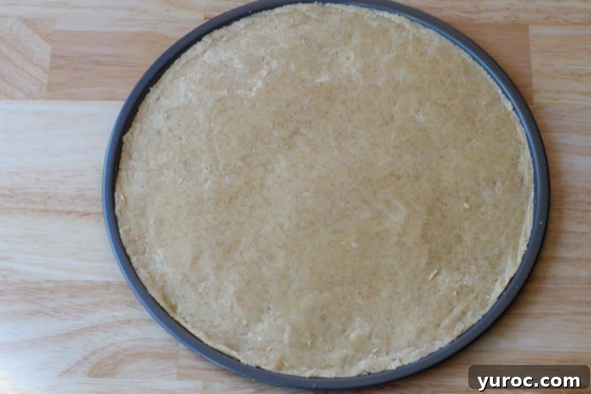 Vibrant Fruit Pizza with Sweet Glaze 6 The shortbread dough is neatly rolled out and pressed onto a 14-inch pizza pan, forming the base for the fruit pizza.