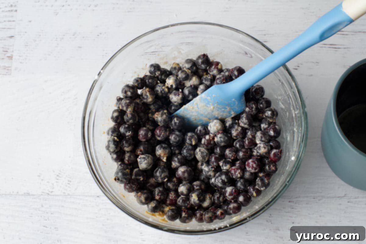 Saskatoons in bowl with other filling ingredients, with a blue spatula