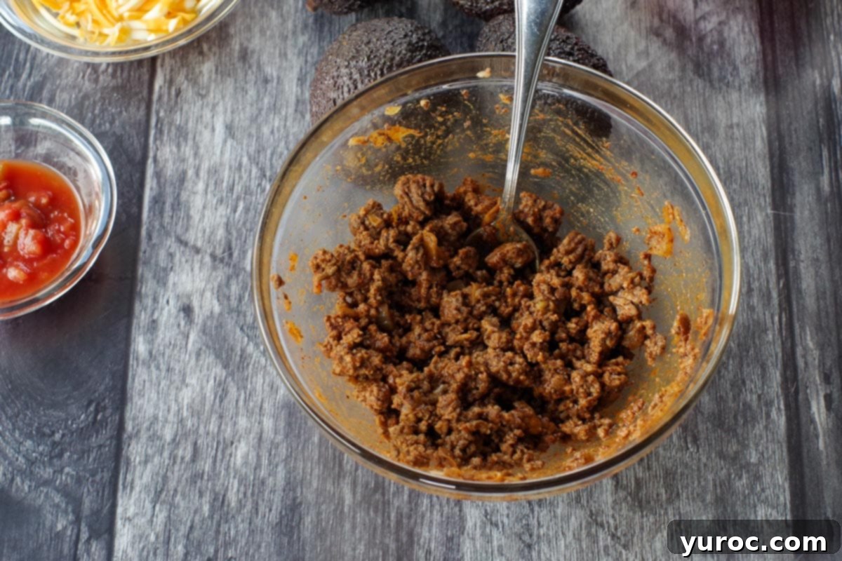 Taco-seasoned ground beef perfectly cooked and resting in a clear glass bowl, accompanied by a serving spoon