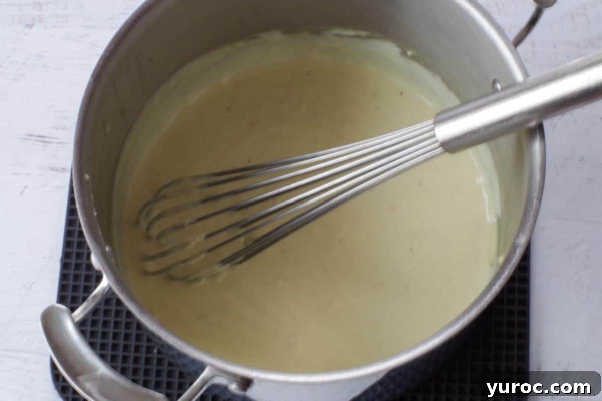 Silky Light Chicken Fettuccine 11 Thickened sauce in a large pot with a whisk.