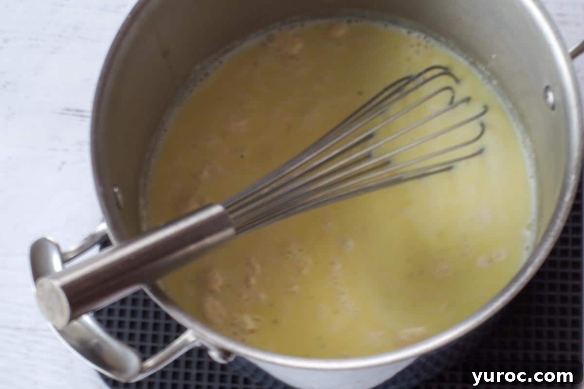 Silky Light Chicken Fettuccine 10 Alfredo sauce thickening in a large pot over medium heat.