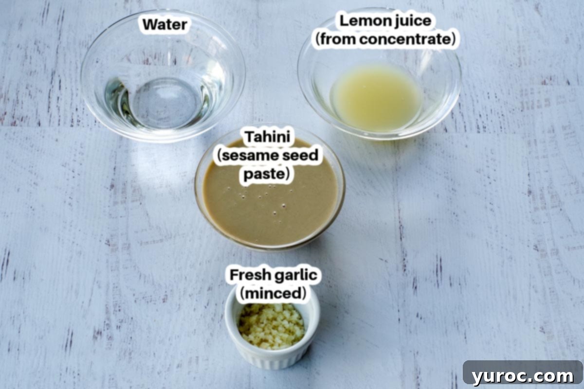 All the ingredients for tahini sauce laid out in small glass bowls, clearly labelled: tahini, chopped garlic, warm water, and lemon juice.