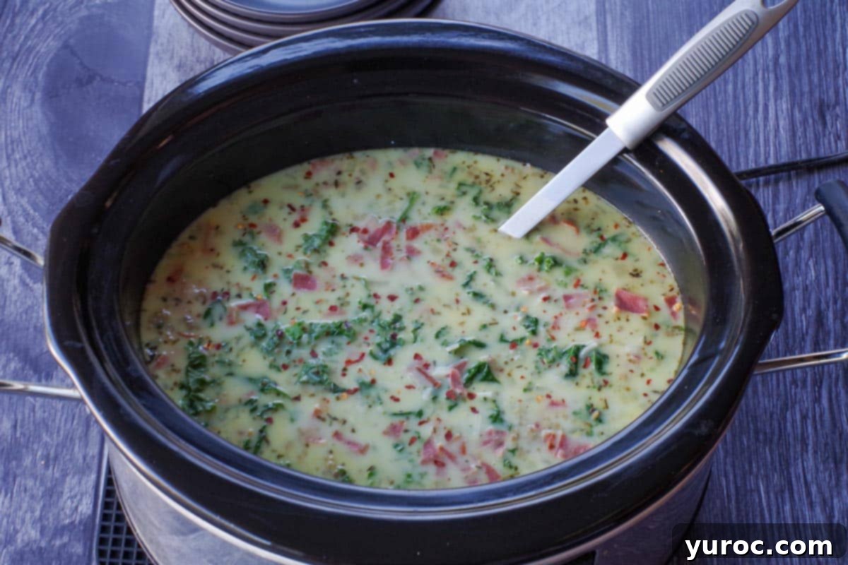 Slow cooker zuppa toscana garnished with turkey bacon and crushed red pepper in a bowl