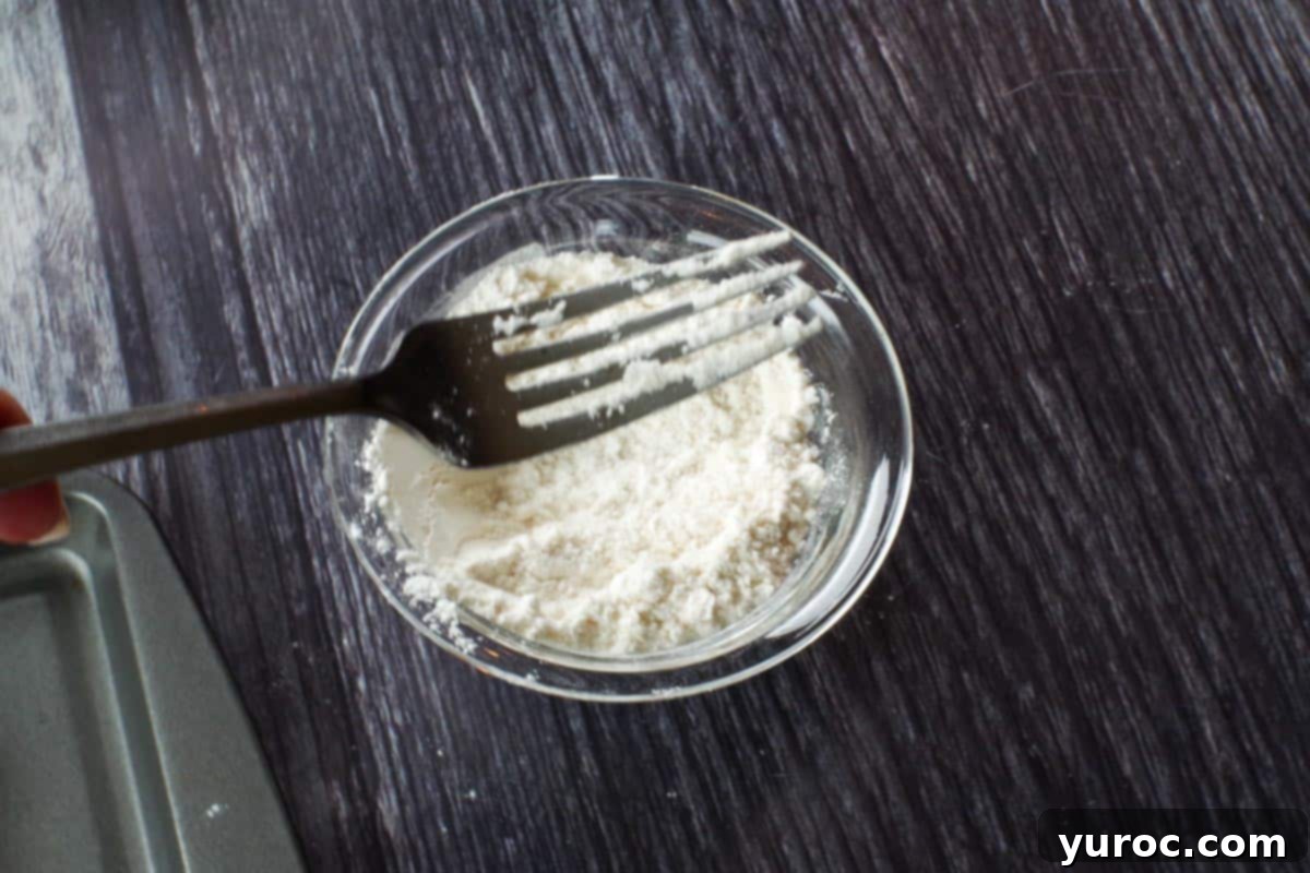 A fork being dipped into a bowl of flour, preparing it for flattening cookie dough