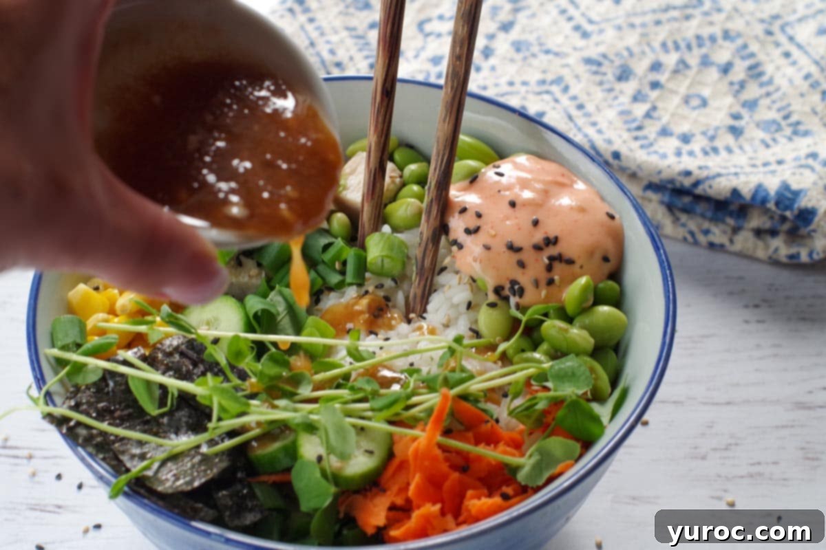 Rich miso dressing being gracefully poured over a vibrant and freshly assembled chicken poke bowl, adding a final touch of flavor.