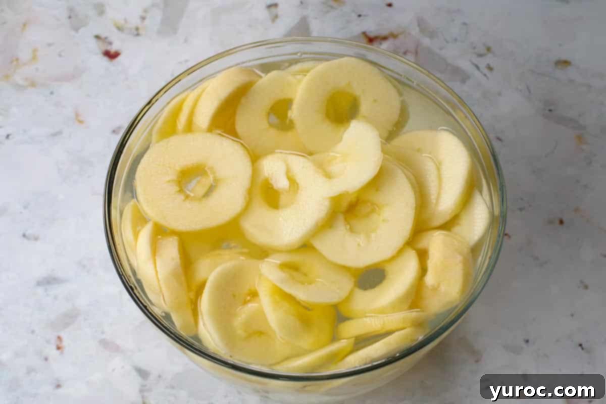 apples cut in circles in a glass bowl with lemon water