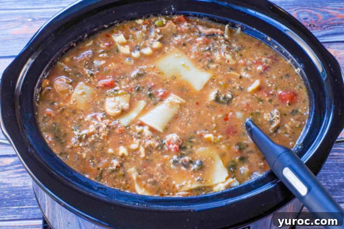 Hearty lasagna soup simmering in a slow cooker, ready to be served with a ladle