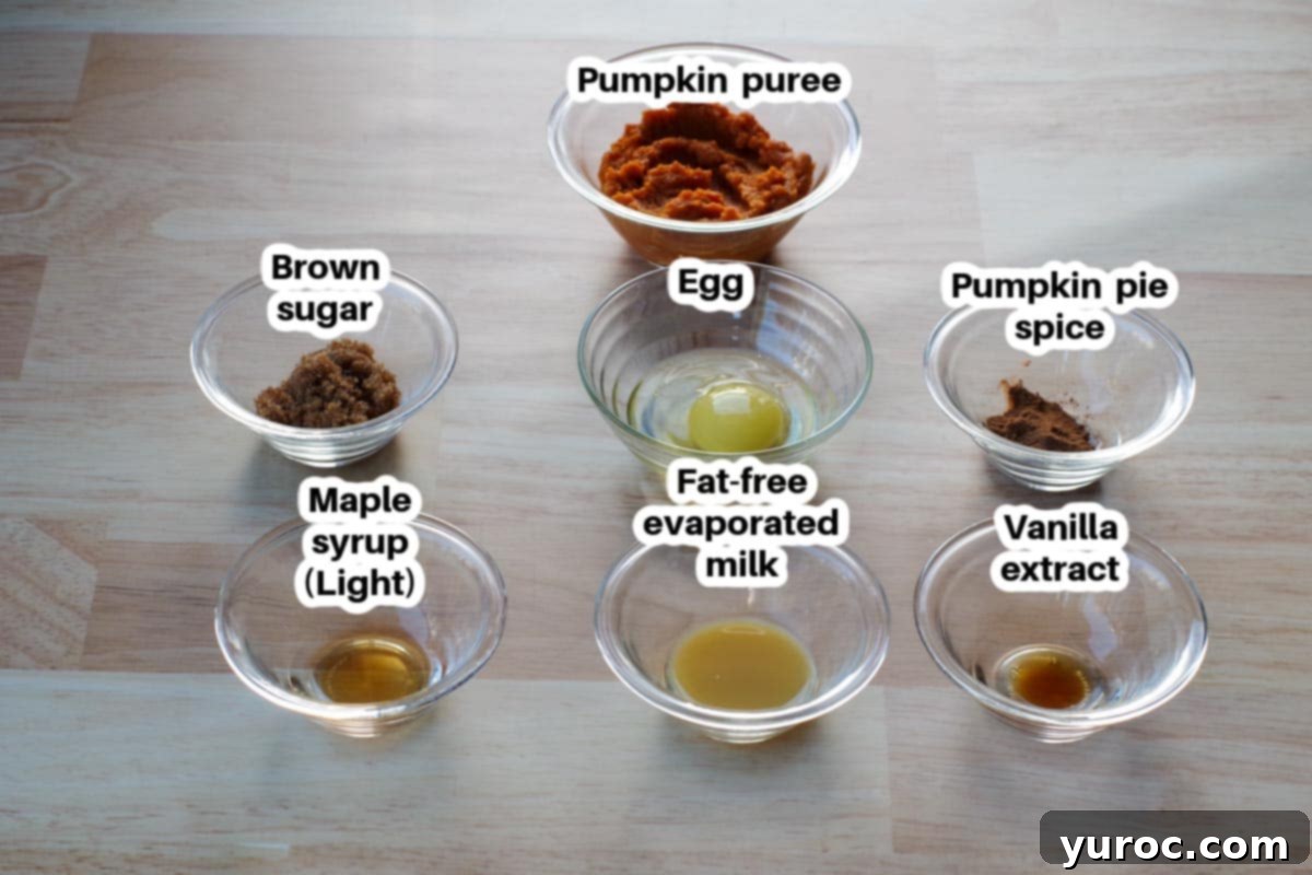 Velvet Pumpkin Mug Bake 3 Carefully arranged ingredients for crustless pumpkin pie in a mug, including pumpkin puree, egg, evaporated milk, brown sugar, pumpkin pie spice, maple syrup, and vanilla extract.