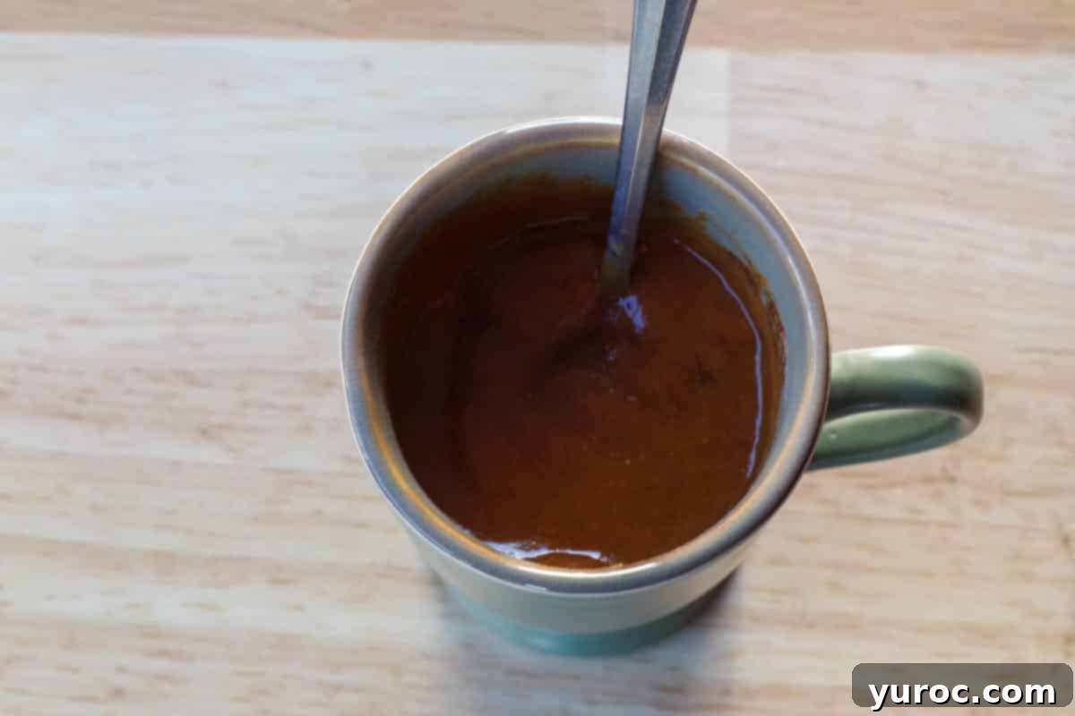 Velvet Pumpkin Mug Bake 5 Crustless pumpkin pie ingredients thoroughly mixed in a mug with a fork, ready for microwaving.