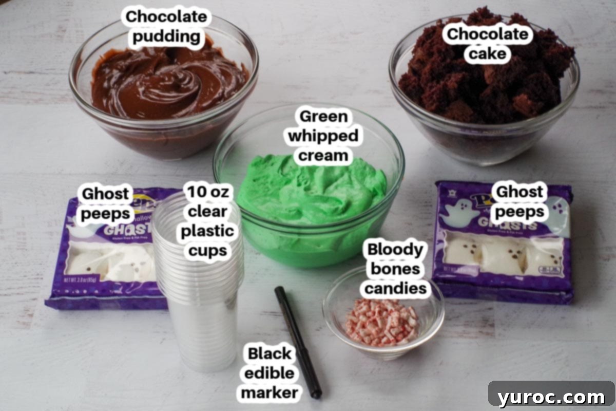 Ingredients for Halloween Dessert Cups in clear glass bowls, each clearly labelled, including cake, pudding mix, whipped cream, ghost peeps, green food coloring, and candy bloody bones.