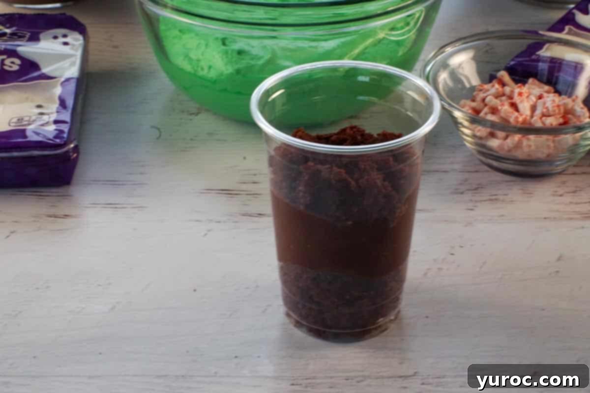 Another layer of crumbled chocolate cake added over the pudding layer in a dessert cup.