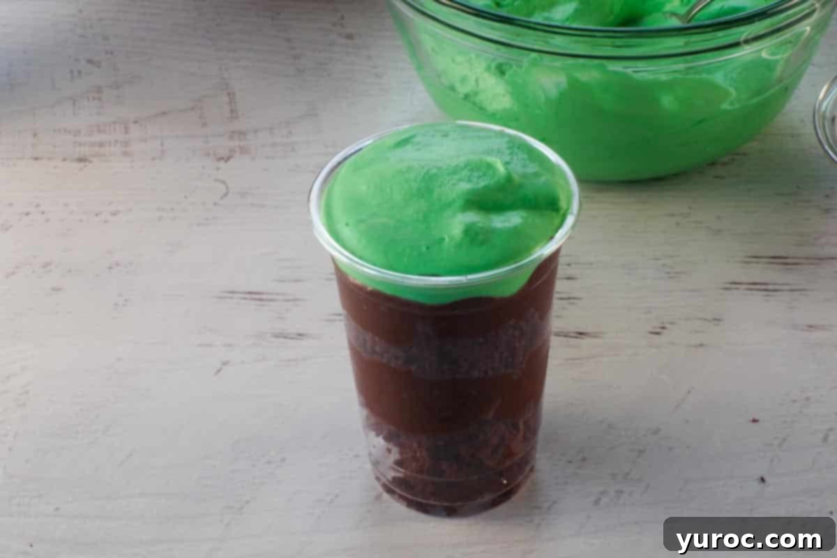 A vibrant green whipped cream layer is piped or spooned on top of the final pudding layer.