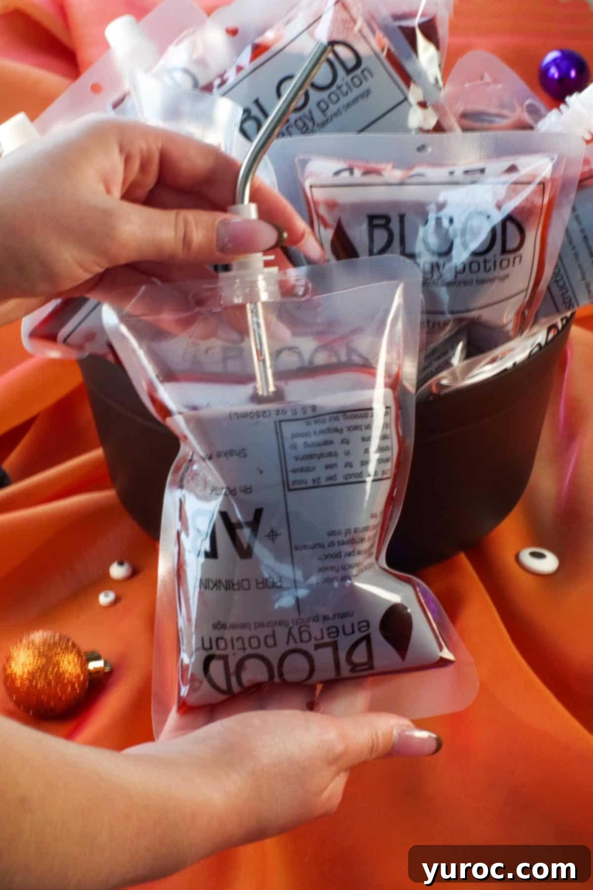 Virgin Blood Bags Halloween 9 A single Halloween blood bag with a straw, prominently displayed in the foreground, with more blood bags chilling in a cauldron behind it.