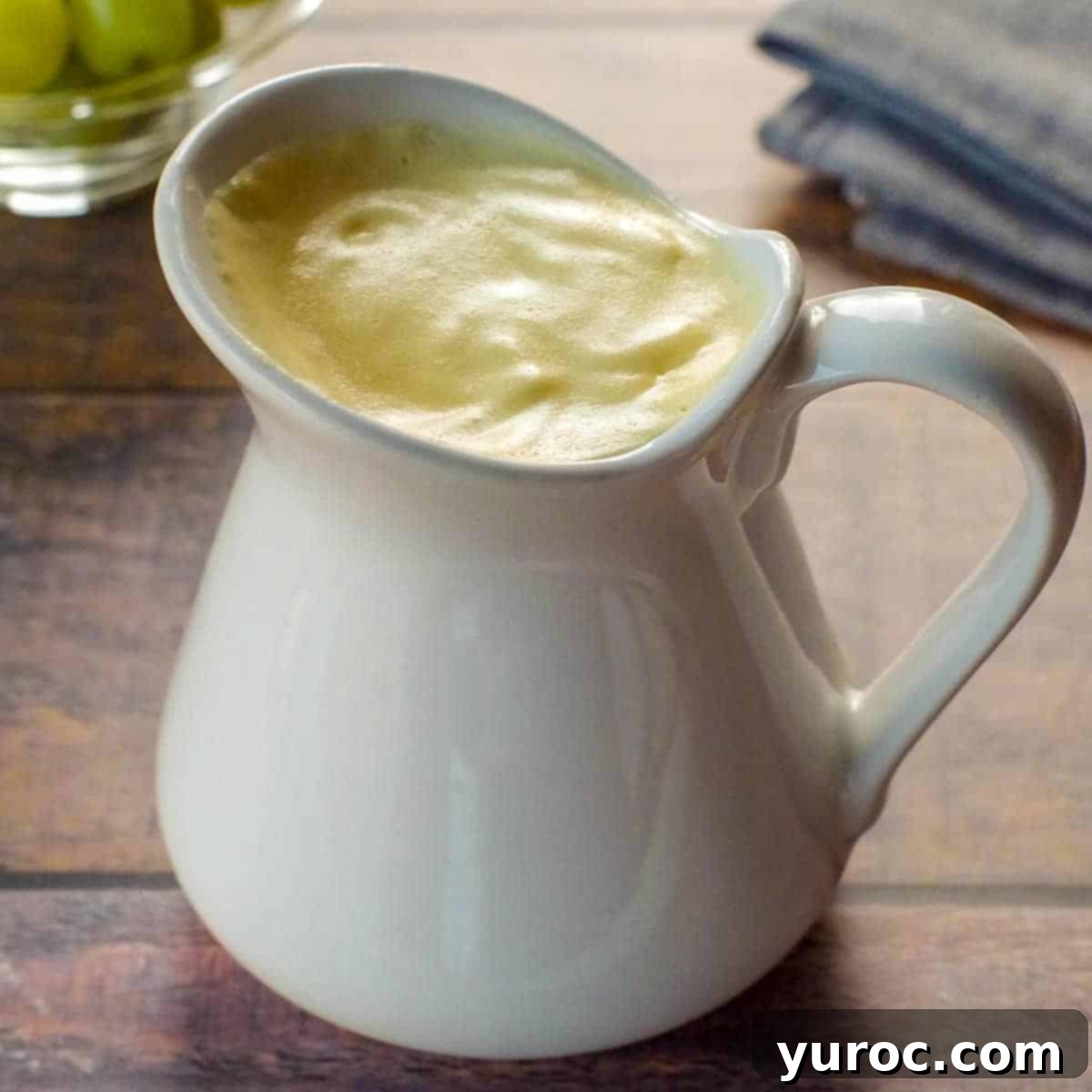 Vibrant Roasted Red Pepper Egg White Bites 11 Healthy Hollandaise sauce in a large white creamer, with a bowl of green grapes in background and grey linen