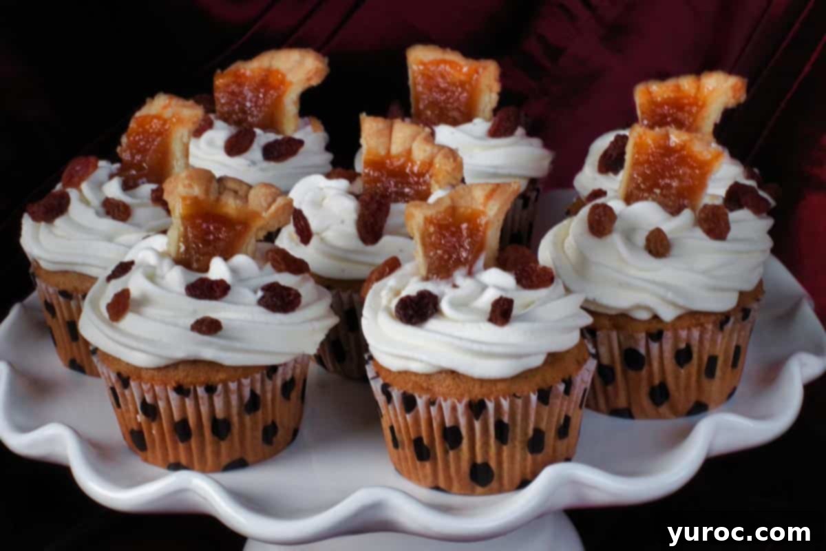 6 butter tart cupcakes on a white cake platter, garnished with raisins and butter tart slices