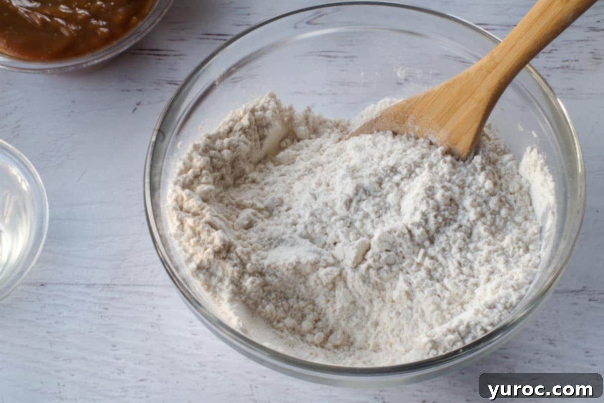 Dry ingredients in a medium glass bowl with a wooden spoon