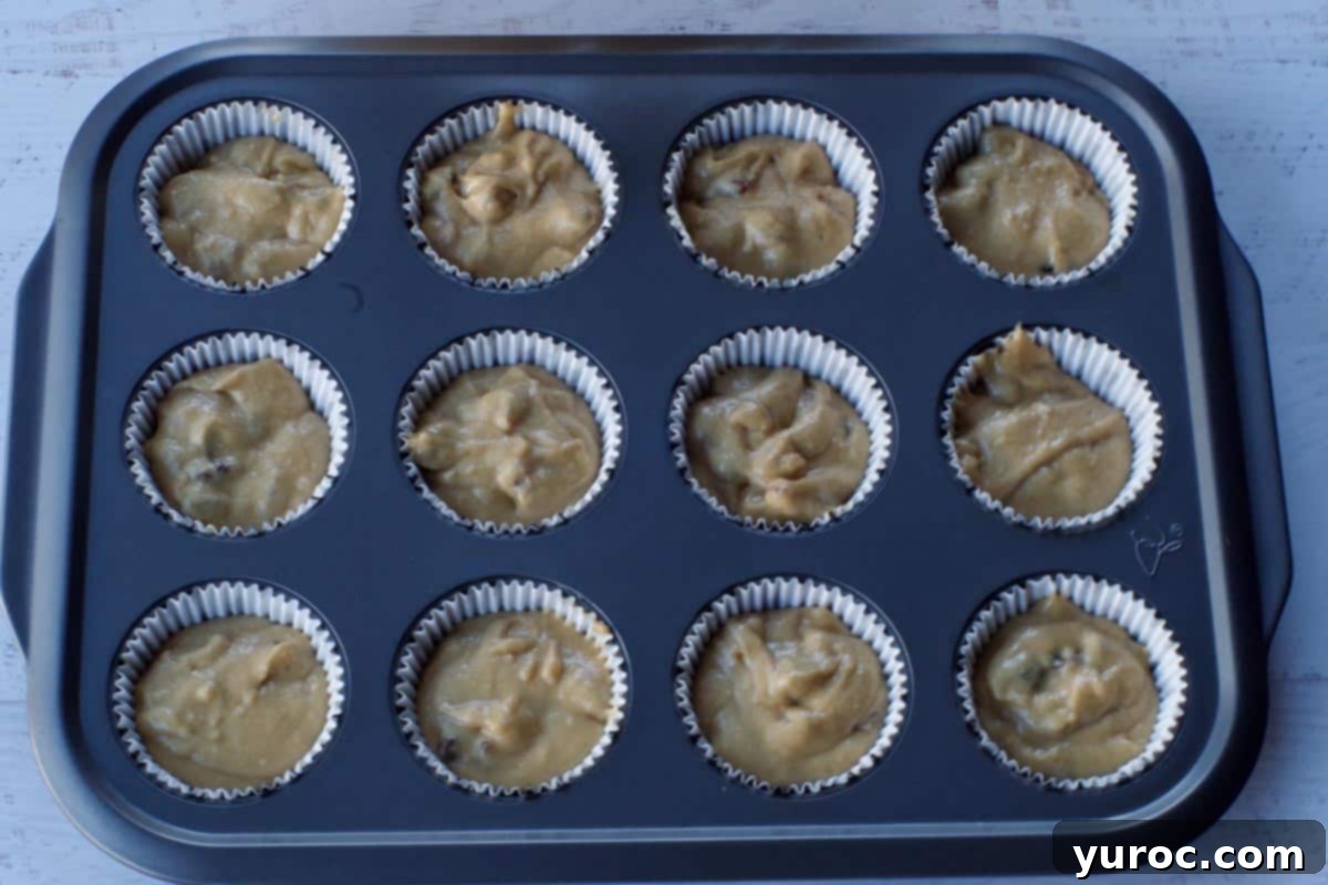Muffin liners filled with cupcake batter in a 12-cup muffin tin