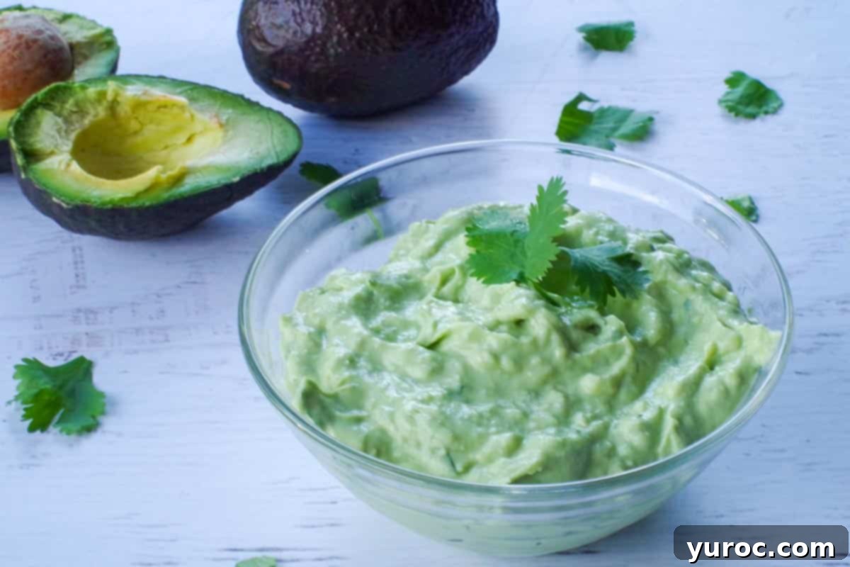 avocado cream sauce in a glass bowl with an avocado in the background