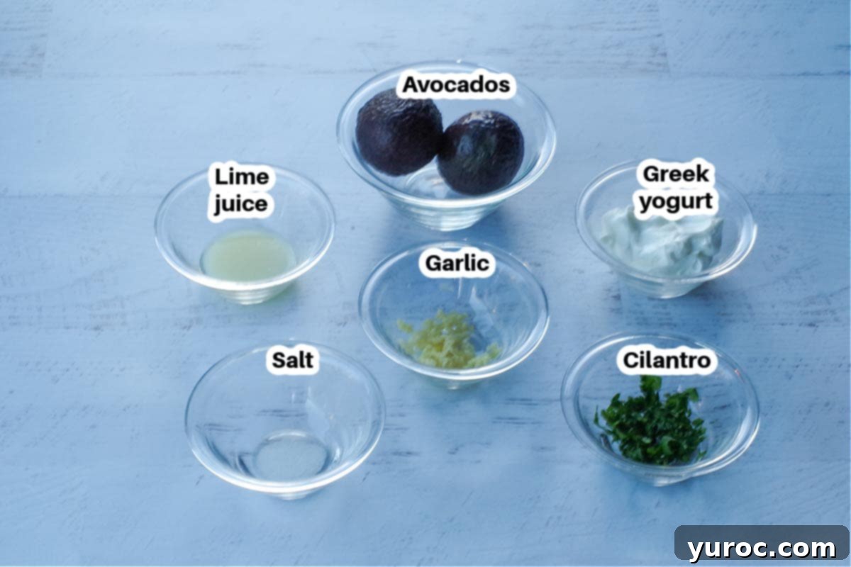ingredients in avocado cream sauce in glass bowls, labelled, on a faux white wood surface