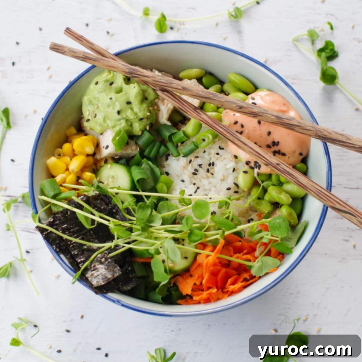 chicken poke bowl with chopsticks laying over the bowl and pea shoots strewn around bowl.