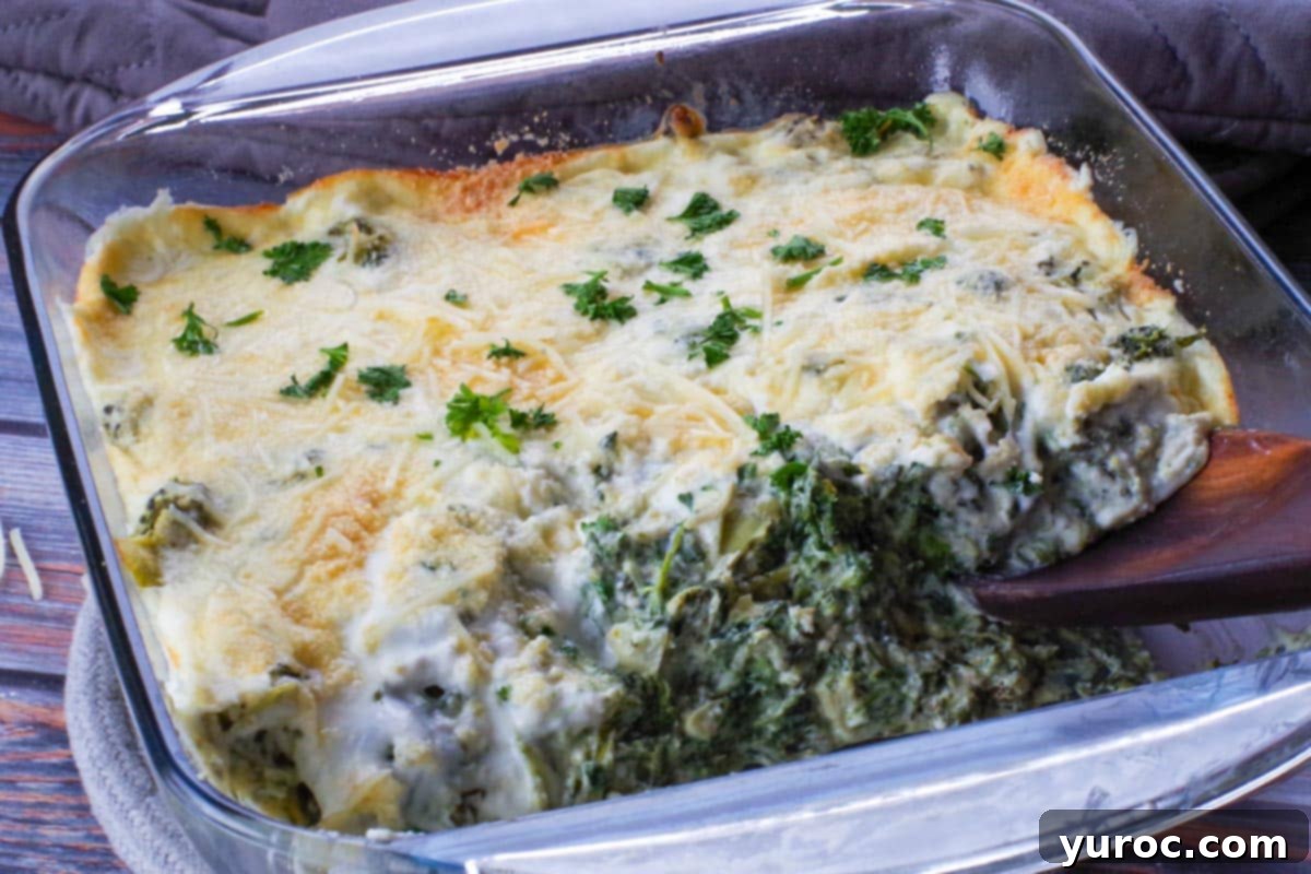 spinach artichoke casserole with some missing and wooden spoon in empty space