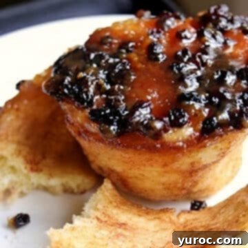 A single, generously sized butter tart cinnamon bun presented on a pristine white plate, promising a deliciously sweet experience