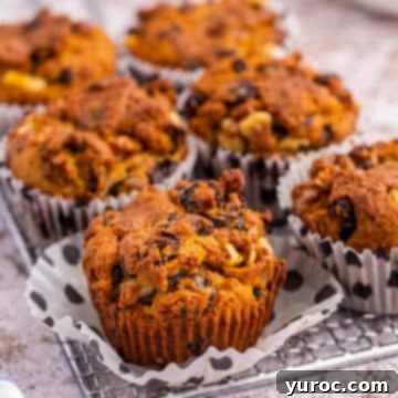 Six golden-brown butter tart muffins artfully arranged on a wire rack, with one muffin showing its tender interior after the paper liner has been removed