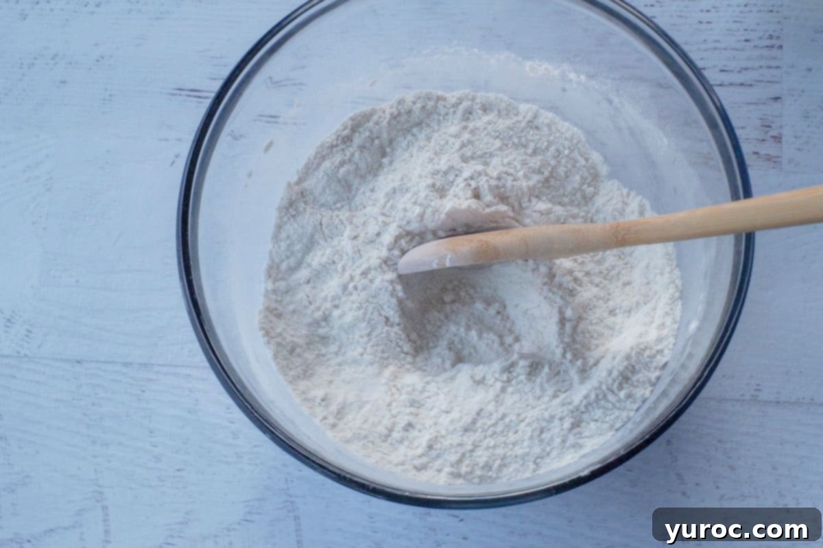 dry ingredients mixed together in large glass bowl with wooden spoon