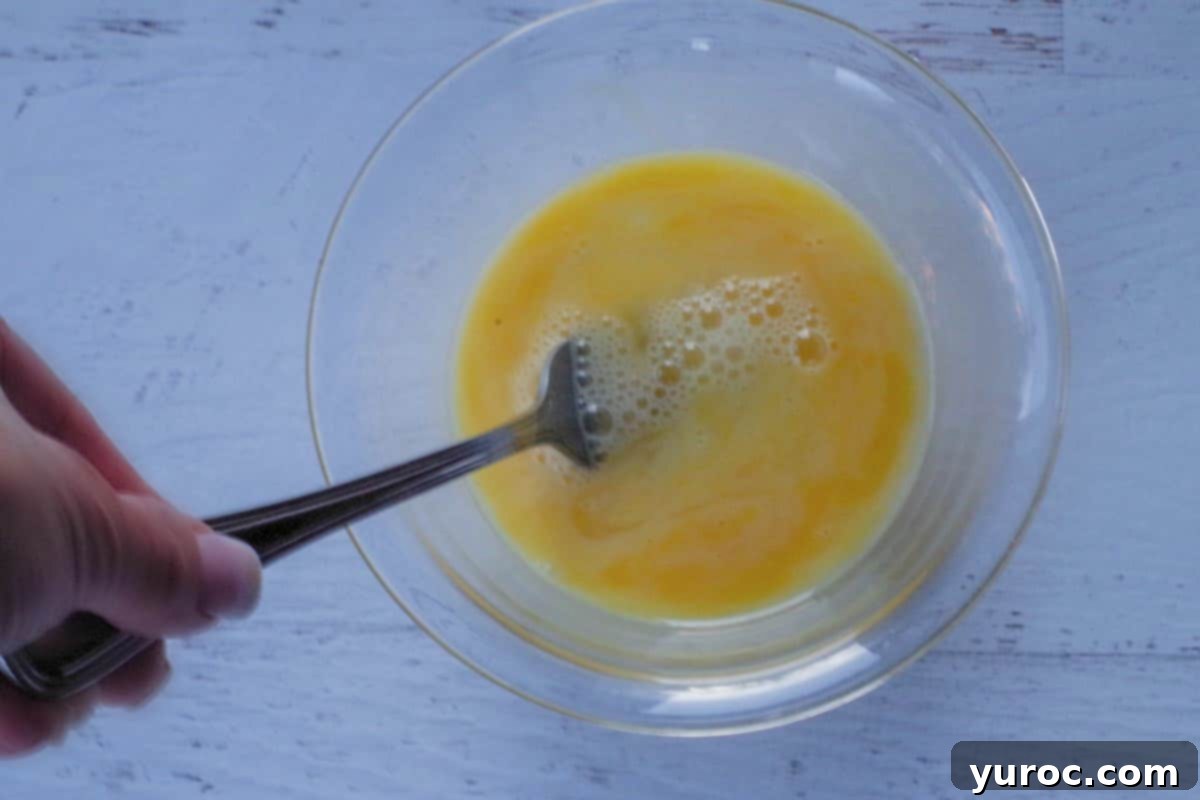 eggs being beaten with fork in glass bowl
