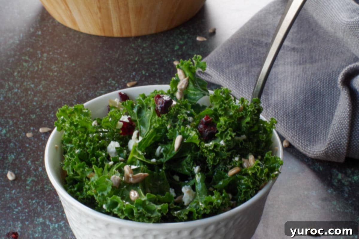 1 serving in white bowl of kale cranberry salad with fork in it