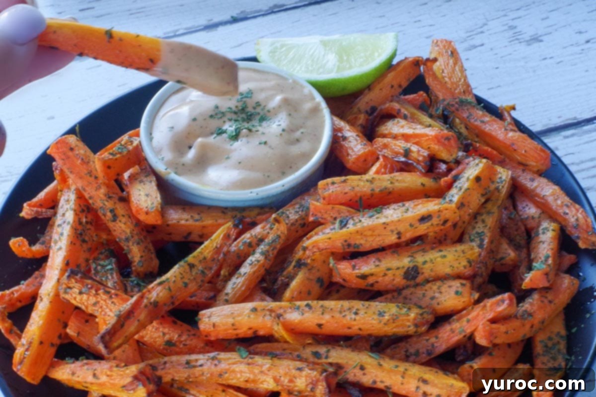 carrot fry being dipped into dip over a plate of more carrot fries