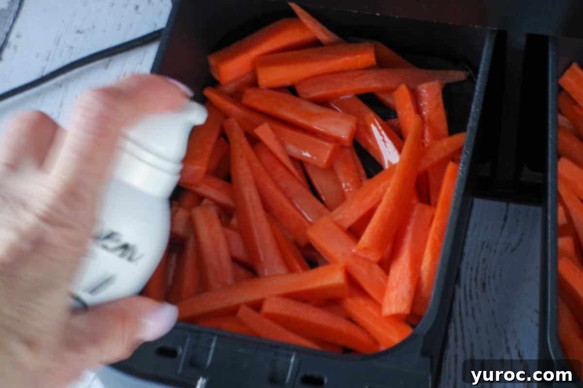 raw carrot fries being sprayed with oil