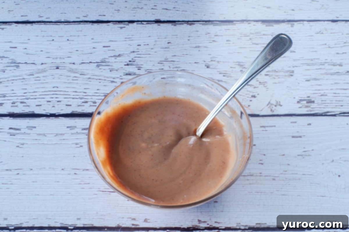 mayonnaise and Chipotle sauce mixed together in glass bowl, with spoon