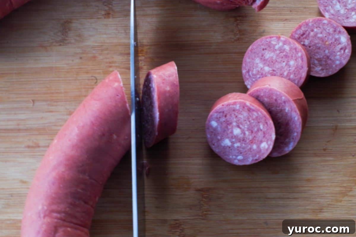 Kielbasa on cutting board, being sliced into uniform ½ inch rounds