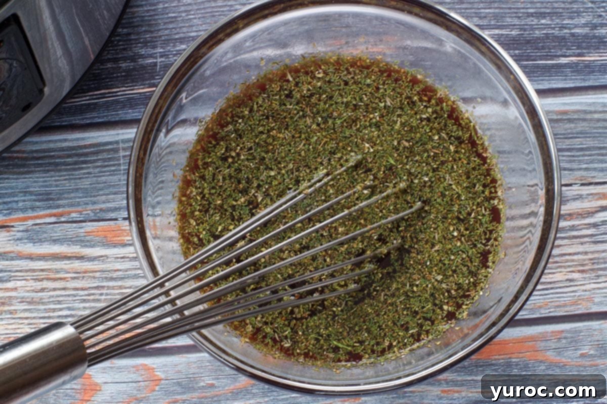 liquid herb mixture in a medium glass bowl, with a whisk